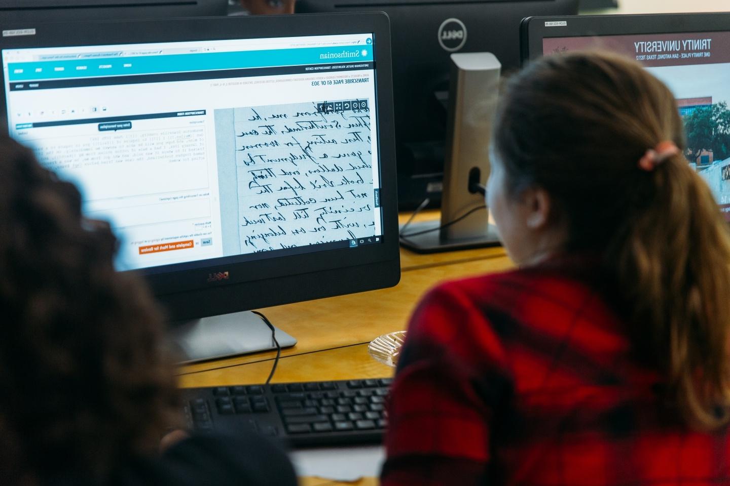 学生看着电脑屏幕比较古代手稿的数字版本和旁边的翻译