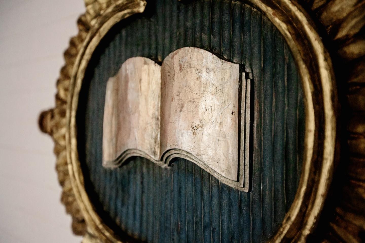 A book open in a circular gold frame